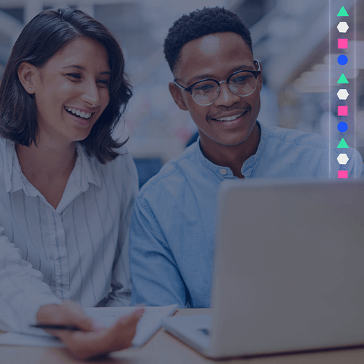 Two people sit together at a desk, smiling and looking at a laptop screen in an office setting. Geometric icons, reflecting GridVizion’s modern style, are displayed vertically along the right side of the image.